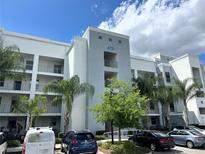 Modern condominium complex featuring a light color scheme, balconies, and neatly landscaped grounds with palm trees at 4751 Clock Tower Dr # 304, Kissimmee, FL 34746