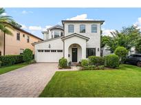 Beautiful two-story white brick home with an attached garage, manicured lawn, and inviting front garden at 528 Greely St, Orlando, FL 32804