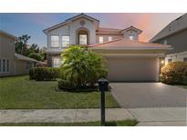 Charming two-story home boasts a red tile roof, neutral stucco exterior, and a well-manicured front yard at 530 Harriswood Ct, Davenport, FL 33837