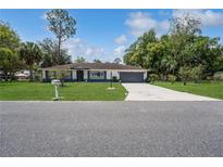 Charming single-story home featuring a well-manicured lawn and a long driveway leading to a two-car garage at 543 Silver Crse, Ocala, FL 34472