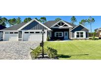 Beautiful home featuring a well-manicured lawn, attractive landscaping, and a three-car garage at 6449 Sw 180Th Cir, Dunnellon, FL 34432