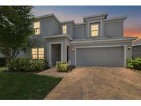 Charming two-story home showcasing a brick driveway, attached two-car garage, and landscaped front yard at dusk at 1292 Cavender Creek Rd, Minneola, FL 34715