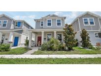 Charming two-story home with a welcoming front porch, beautiful landscaping, and a vibrant red front door at 2345 Volunteer Ave, Kissimmee, FL 34744