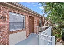 Brick condo building with a brown door, white railing, and large window offering curb appeal at 2517 Caper Ln # 207, Maitland, FL 32751