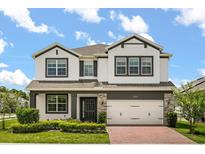 Beautiful two-story home featuring a white stucco facade, stone accents, well-manicured landscaping, and a brick driveway at 2541 Leyland Cypress Ln, Sanford, FL 32773