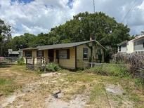 Modest single-story home with yellow siding, mature trees, and a slightly overgrown front yard at 2601 Tennessee Rd, Lakeland, FL 33815