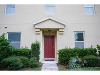 Inviting front entrance with a classic red door, trimmed bushes, and muted neutral stucco at 3569 Seneca Club Loop # 13, Orlando, FL 32808