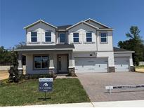 Two-story home boasts a three-car garage, gray accents, and a welcoming front porch at 441 Lady Palm St, Apopka, FL 32703