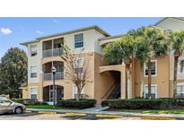 Multi-level condo building with beige exterior, palm trees, screened patios and convenient parking at 6214 Stevenson Dr # 208, Orlando, FL 32835