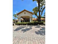 Welcoming clubhouse entrance with a covered entryway, beautiful stone pathway and manicured landscaping at 8010 Tuscany Way # 3102, Davenport, FL 33896