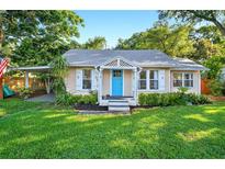 Charming single-story home with a bright blue front door, lush lawn, and covered carport at 815 E 11Th Ave, Mount Dora, FL 32757