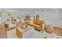 Bright, open-concept living room featuring a leather sofa, hardwood floors, and kitchen in the background at 107 Hilltop Dr, Longwood, FL 32750