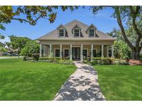 Beautiful single-Gathering home featuring a manicured lawn, inviting porch, and mature trees on a sunny day at 19554 Spring Oak Dr, Eustis, FL 32736