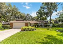 Charming single-story home featuring a well-manicured lawn, lush landscaping, and a stone-accented facade with attached two-car garage at 205 Stevenage Dr, Longwood, FL 32779