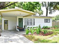 Charming single-story home with a quaint, landscaped front yard and a welcoming covered entrance with an olive colored front door at 3519 Amigos Ave, Orlando, FL 32808