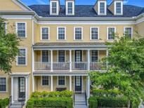 Attractive three-story townhome featuring a second-story balcony and manicured landscaping at 4584 Virginia Dr, Orlando, FL 32814