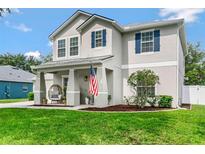 Charming two-story home with a well-manicured lawn, blue shutters, and inviting front porch with comfortable seating at 486 Shirley Dr, Apopka, FL 32712