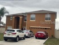 Two-story tan home with an attached two-car garage and driveway parking at 547 Big Sioux Ct, Kissimmee, FL 34759