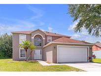 Charming two-story home featuring a two-car garage, manicured lawn, and inviting front entrance at 636 Milan Dr, Kissimmee, FL 34758