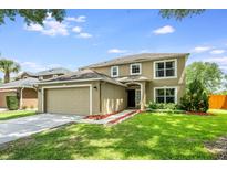 Two-story home with a two-car garage, manicured lawn, walkway, and neutral-colored stucco exterior at 100 Monterey Oaks Dr, Sanford, FL 32771
