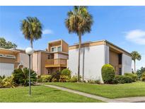 Condo exterior with manicured landscaping and palm trees against a blue sky at 1051 S Highland St # 7D, Mount Dora, FL 32757