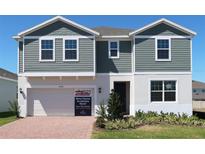 Inviting two-story home with neat landscaping, a two-car garage, and a brick driveway at 14568 Crestavista Ave, Clermont, FL 34714
