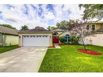Charming single-story home featuring a well-manicured lawn, two car garage, and bright red front door at 2031 Wekiva Reserve Blvd, Apopka, FL 32703