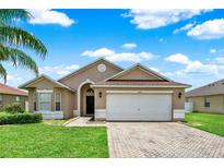 Charming single-story home with a paved driveway, a well-manicured lawn, and a two-car garage at 2713 Eagle Glen Cir, Kissimmee, FL 34746