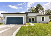 Charming single-story home with a blue garage door, well-kept lawn, and a modern gray exterior at 4345 Sw 143Rd Lane Rd, Ocala, FL 34473