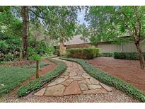 Inviting stone pathway leading to the home, framed by lush greenery and mature trees at 4702 Shorecrest Dr, Orlando, FL 32817