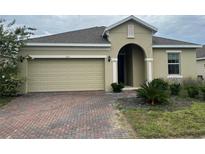Charming single-story home featuring a brick driveway and a two-car garage at 512 Novara Way, Davenport, FL 33837