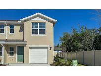 Beige two-story home featuring an attached garage, complemented by a manicured lawn and a clear blue sky at 535 Zinfandel Dr, Daytona Beach, FL 32117