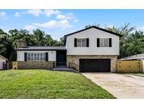 Charming two-story home with stone accents, a well-manicured lawn, and a black garage door at 608 Pearl Rd, Winter Springs, FL 32708