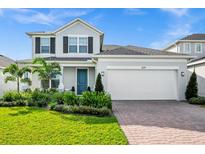 Charming two-story home featuring lush landscaping, brick driveway and two car garage at 609 Big Pine Ave, Minneola, FL 34715