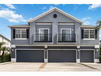 Stylish townhome featuring a gray exterior, multiple garage doors, and quaint second-story balconies at 6484 S Goldenrod Rd # 41A, Orlando, FL 32822
