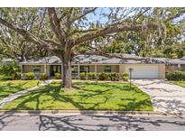 Charming single story home featuring a lush front yard with a well manicured lawn, mature tree, and inviting covered porch at 708 Valencia Ct, Winter Garden, FL 34787