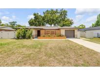 Charming single-story home featuring unique wood accents, a well-maintained lawn, and attached garage at 879 Tamerlane St, Deltona, FL 32725