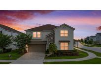 Charming two-story home featuring stone accents, a paved driveway, and lush landscaping at dusk at 8951 Hilton Ridge Ave, Kissimmee, FL 34747