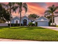 Charming blue home boasts a well-manicured lawn, lush landscaping, and swaying palm trees at 2237 Wintermere Pointe Dr, Winter Garden, FL 34787