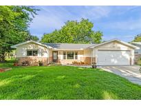 Charming single-story home featuring a well-manicured lawn, brick accents, and an attached garage at 241 Brittany Ave, Port Orange, FL 32127