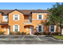 Inviting two-story condo featuring a peach exterior, white-framed windows, and a well-maintained front landscape at 2717 Camaro Dr, Kissimmee, FL 34746