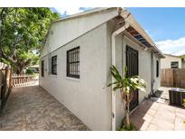 Side view of a single-story home featuring stucco walls, barred windows, and a stone-paved pathway leading to the entrance at 320 Eaton St, Maitland, FL 32751