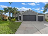 Charming two-story home with a three-car garage, gray siding and palm trees in the front yard at 3640 Sail Harbor Dr, Kissimmee, FL 34746