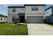 Two-story home with a well-manicured lawn, a gray two-car garage, and a cozy, covered front porch at 3823 Spruce Creek Dr, Lakeland, FL 33811
