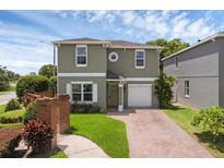 Charming two-story home with brick driveway, manicured lawn, and attached one-car garage at 5852 Mariposa Cove Ln, Orlando, FL 32822