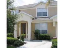 Inviting two-story townhome featuring a covered entry, tan stucco exterior, and well-maintained landscaping at 7682 Sir Kaufmann Ct, Kissimmee, FL 34747