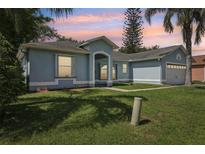 Charming single-story home with a well-manicured lawn, side garage, and tropical trees at 857 Marquis Ct, Kissimmee, FL 34759