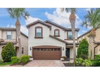 Charming two-story home featuring a brown garage door, tile roofing, and beautiful landscaping, including palm trees at 8912 Rhodes St, Kissimmee, FL 34747