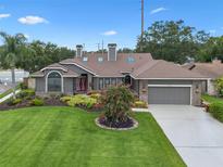 Stunning exterior of home featuring a manicured lawn, mature landscaping, and a two car garage at 9324 Carolview Way, Orlando, FL 32836