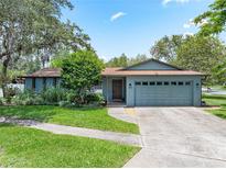 Charming single-story home with lush landscaping, a well-manicured lawn and an attached two car garage at 9543 Buxton, Orlando, FL 32817